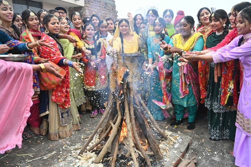 زنان و دختران جوان هندی در آستانه جشنواره سنتی لوهری (Lohri festival)، برنج پف کرده، شیرینی و آجیل آسیاب شده را در آتش می اندازند؛ منبع: theguardian؛ عکاس: Narinder Nanu