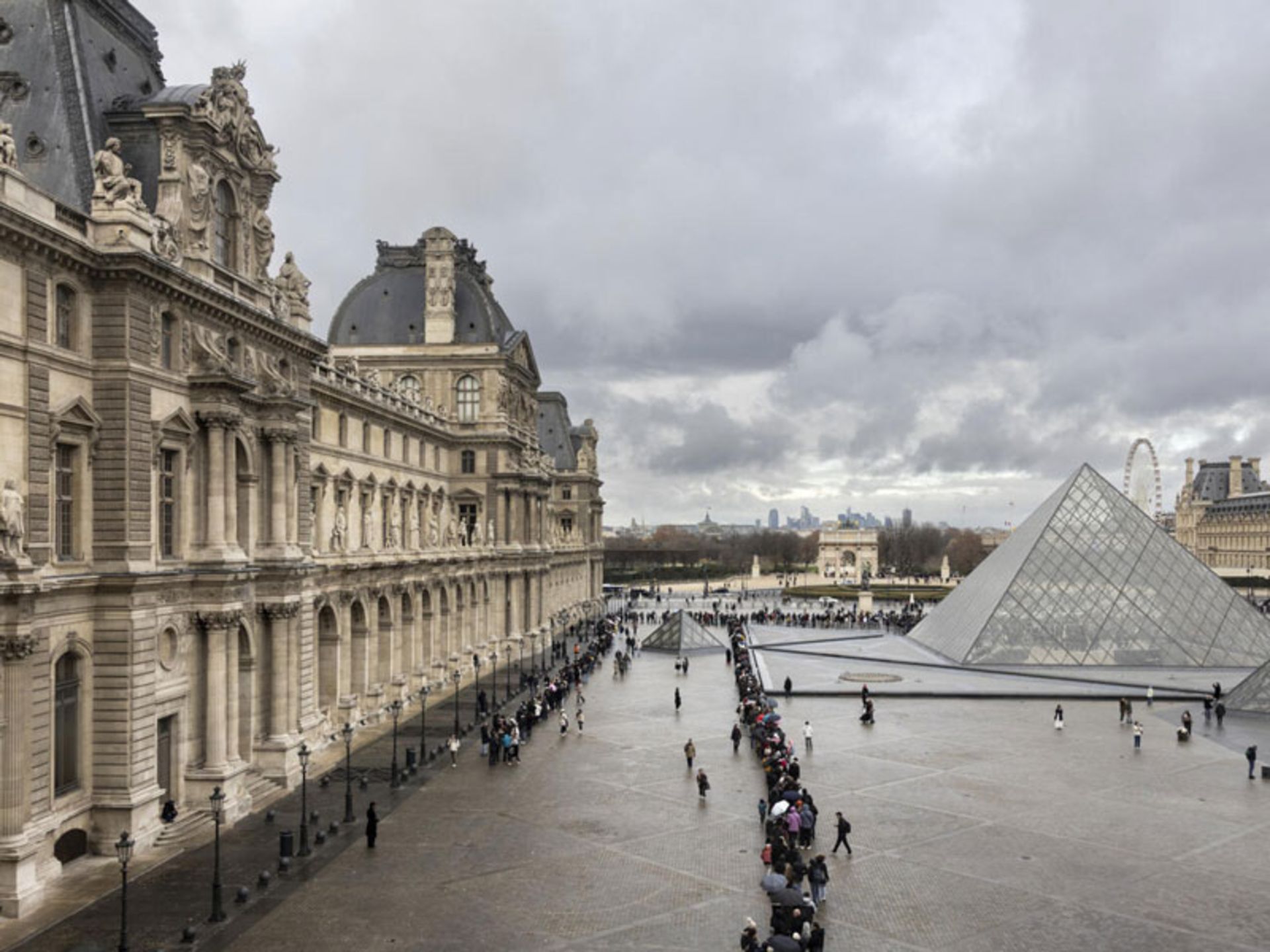 نمای گسترده از محوطه لوور، هرم و صف طولانی مردم