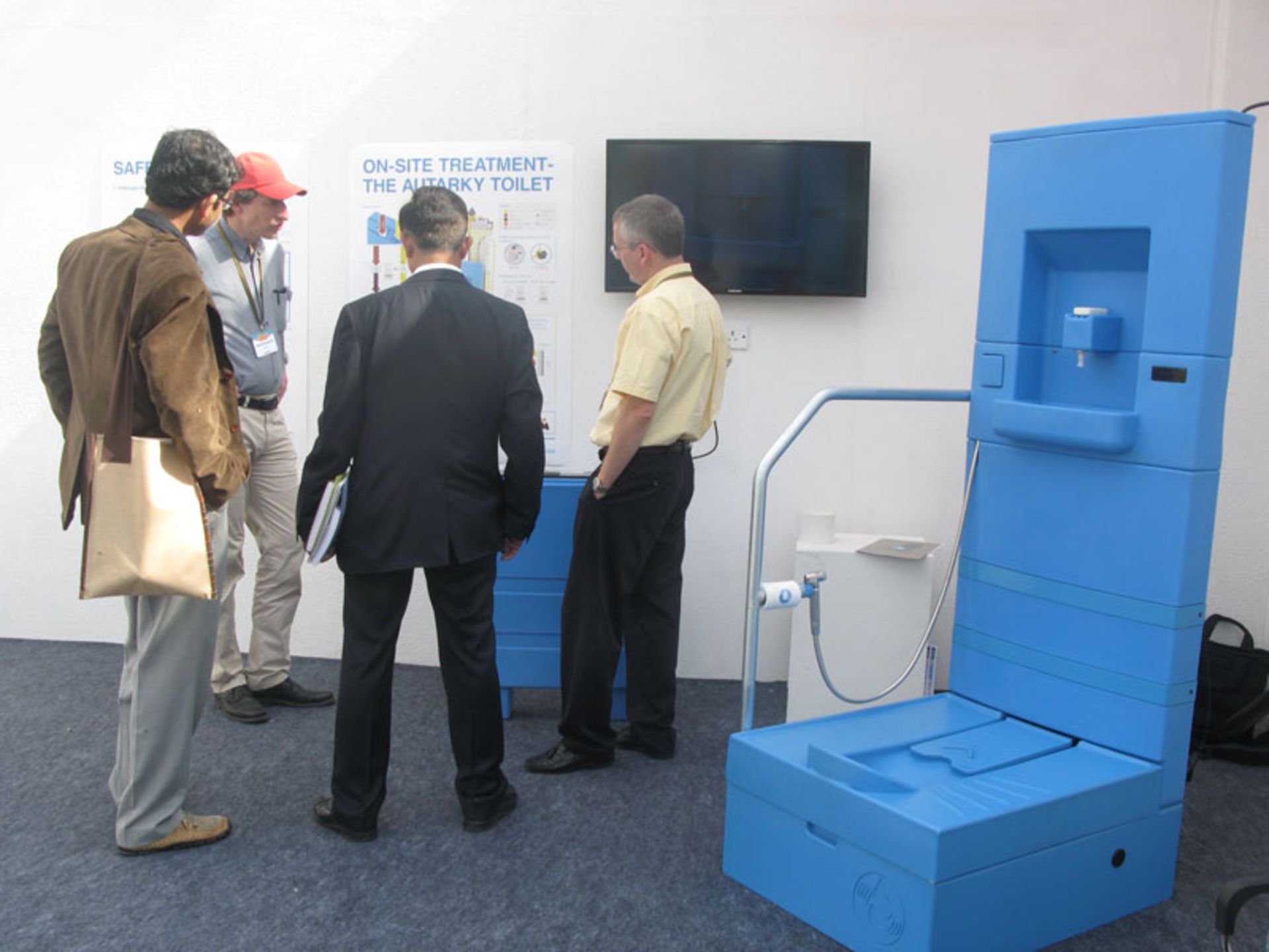 گروهی از کارشناسان در حال بررسی و توضیح اجزای توالت آبی رنگ مدرن و بهداشتی بلو دایورژن