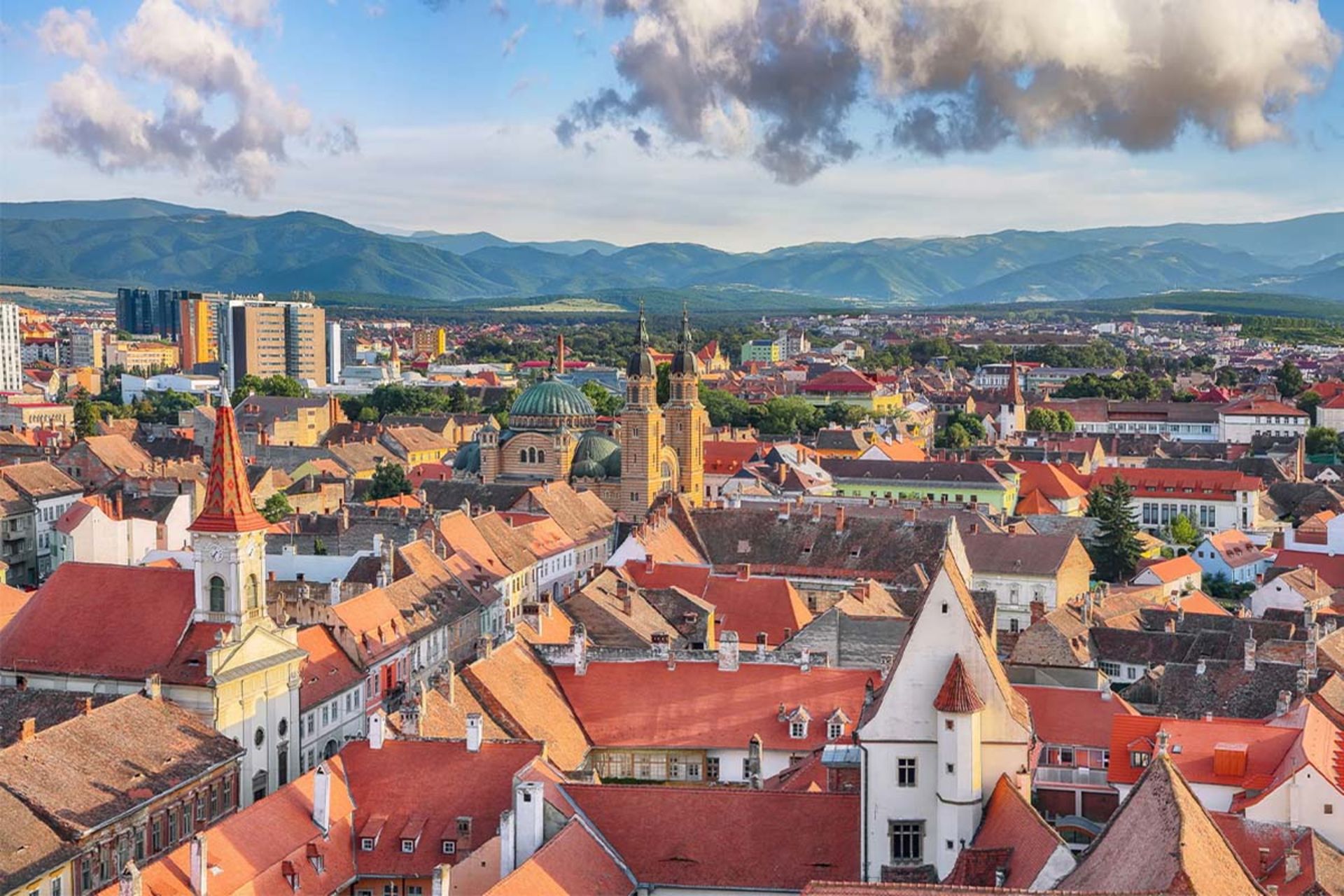 نمای پانوراما از سقف‌های قرمز شهر قدیمی سیبیو (رومانی) با کوه‌های پس‌زمینه