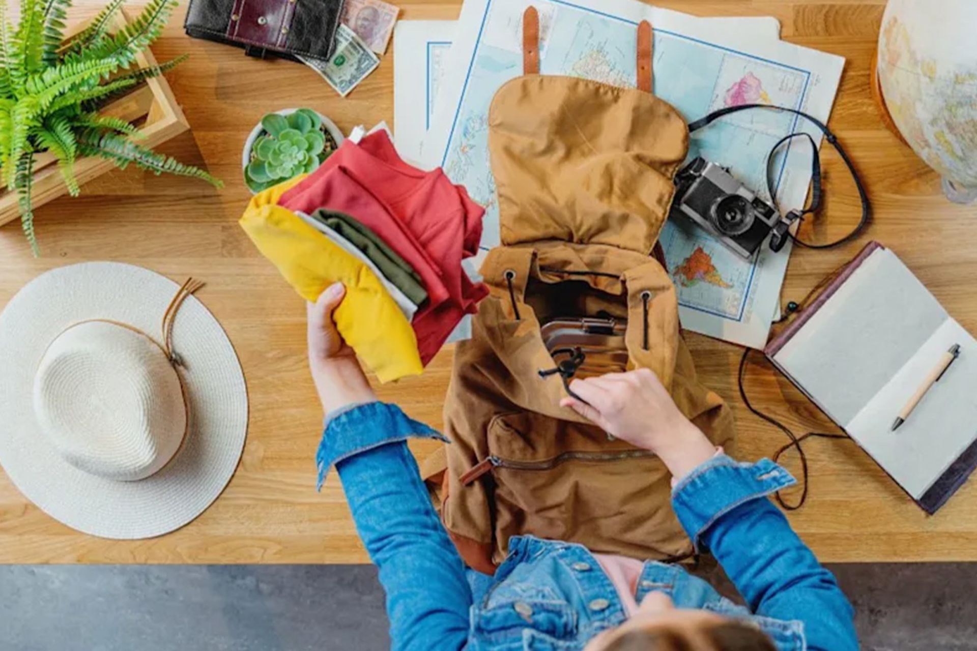 عادات عجیب نسل Z در سفر؛ ارزان و بهشدت هوشمندانه! 3 نمای از بالا از فردی که لباسهای سبک را در کولهپشتی میگذارد