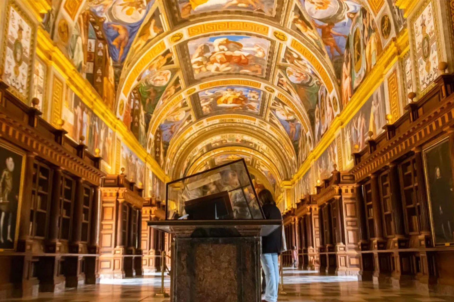 تالار اصلی کتابخانه ال اسکوریال اسپانیا با سقف طاق‌دار رنگارنگ و قفسه‌های چوبی قهوه‌ای