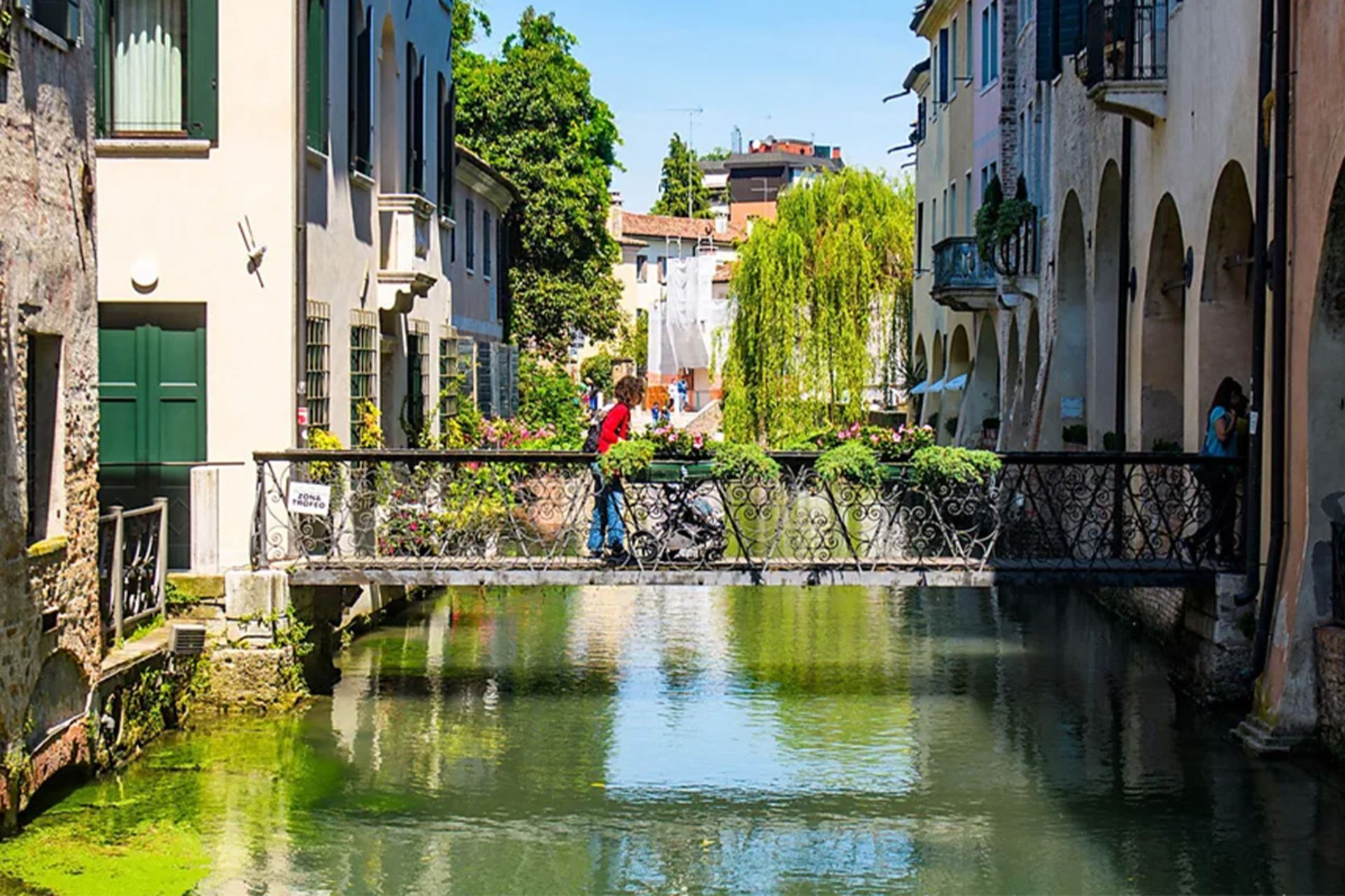 کانال آبی سرسبز در شهر ترویزو با پل و خانه‌های قدیمی