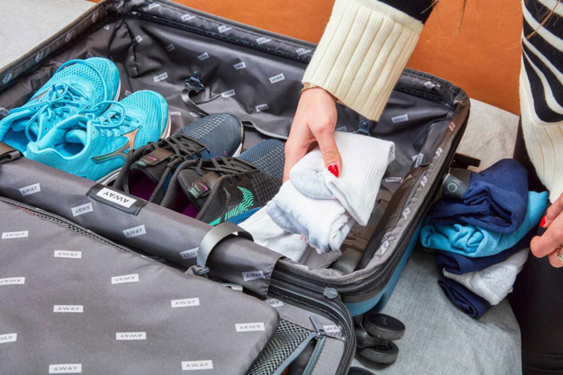 دست زنی در حال چیدن جوراب و کفش ورزشی در چمدان