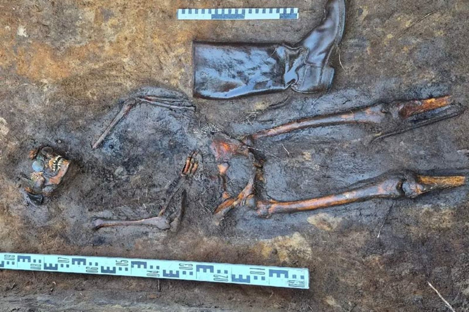 یک اسکلت کامل در کنار چکمه‌های چرمی