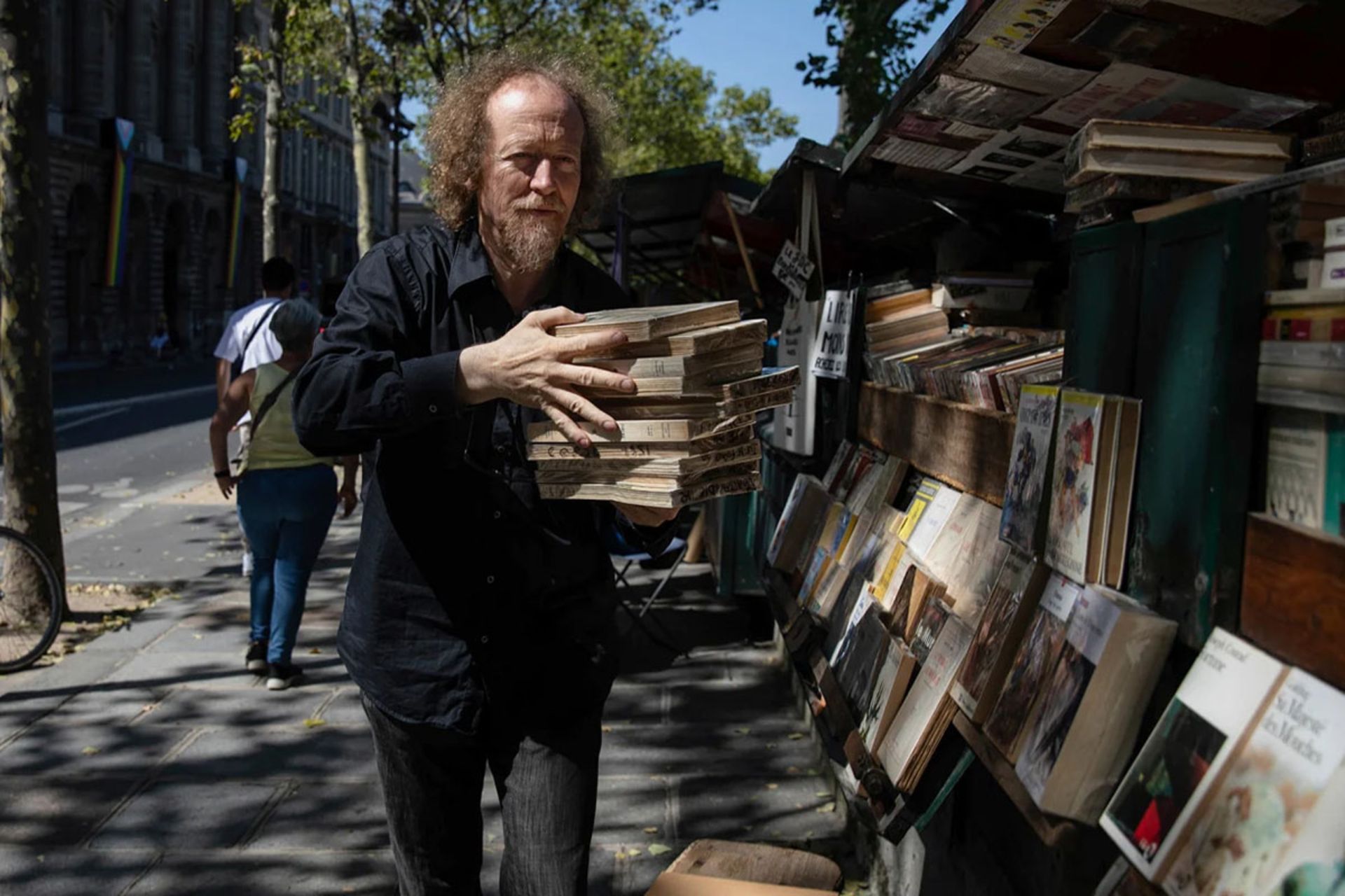 بزرگترین کتابفروشی روباز جهان چگونه زنده مانده است؟ 3 یک کتابفروش پاریسی در حال کار در غرفه