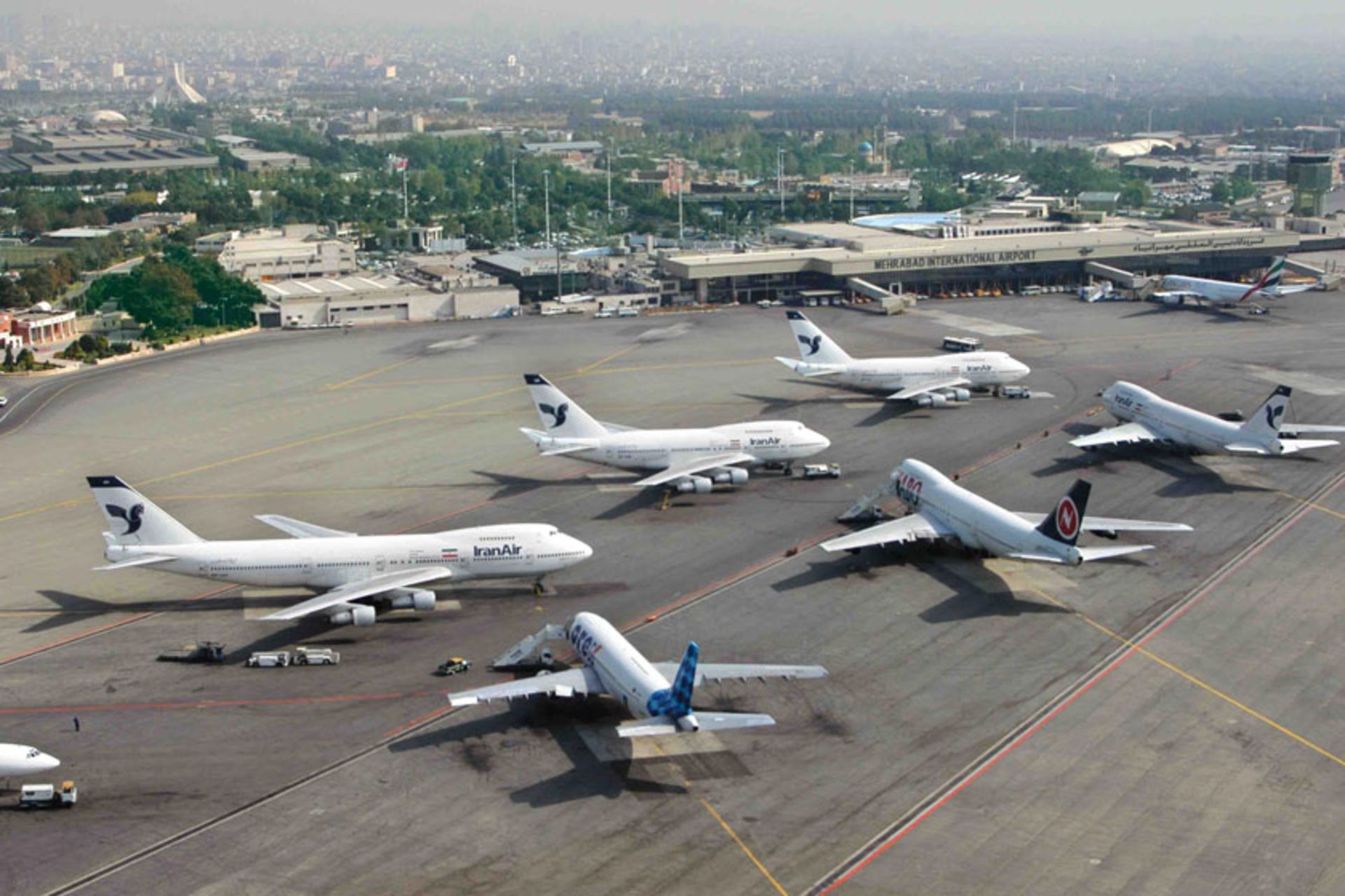 عکس هوایی از هواپیماها در فرودگاه مهرآباد با پس زمینه برج آزادی و شهر تهران